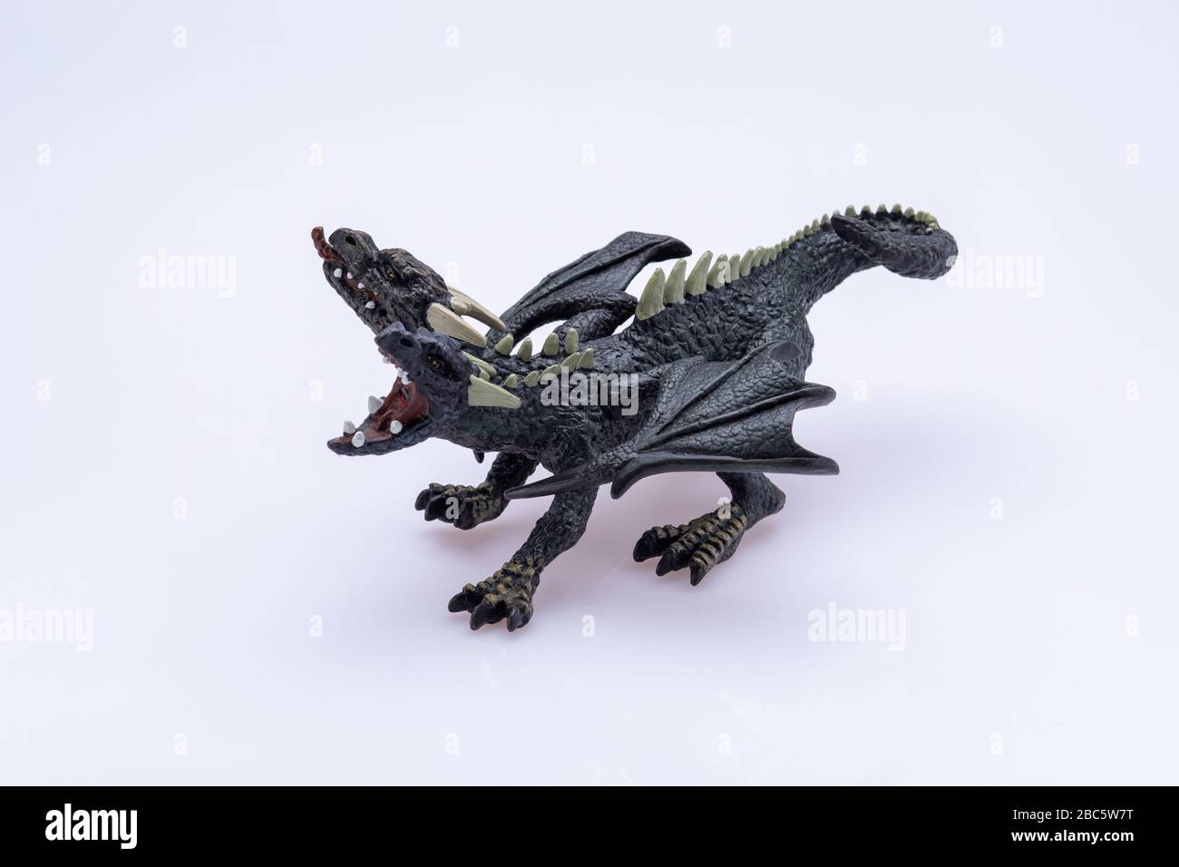 double-headed dragon toy isolated in front a white background. On of its mouths is wide open while the other is closed with the tong going out Stock Photo
