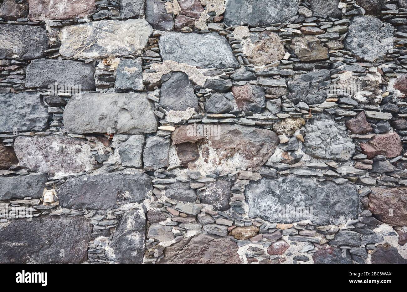 Uneven real stone wall background or texture. Stock Photo