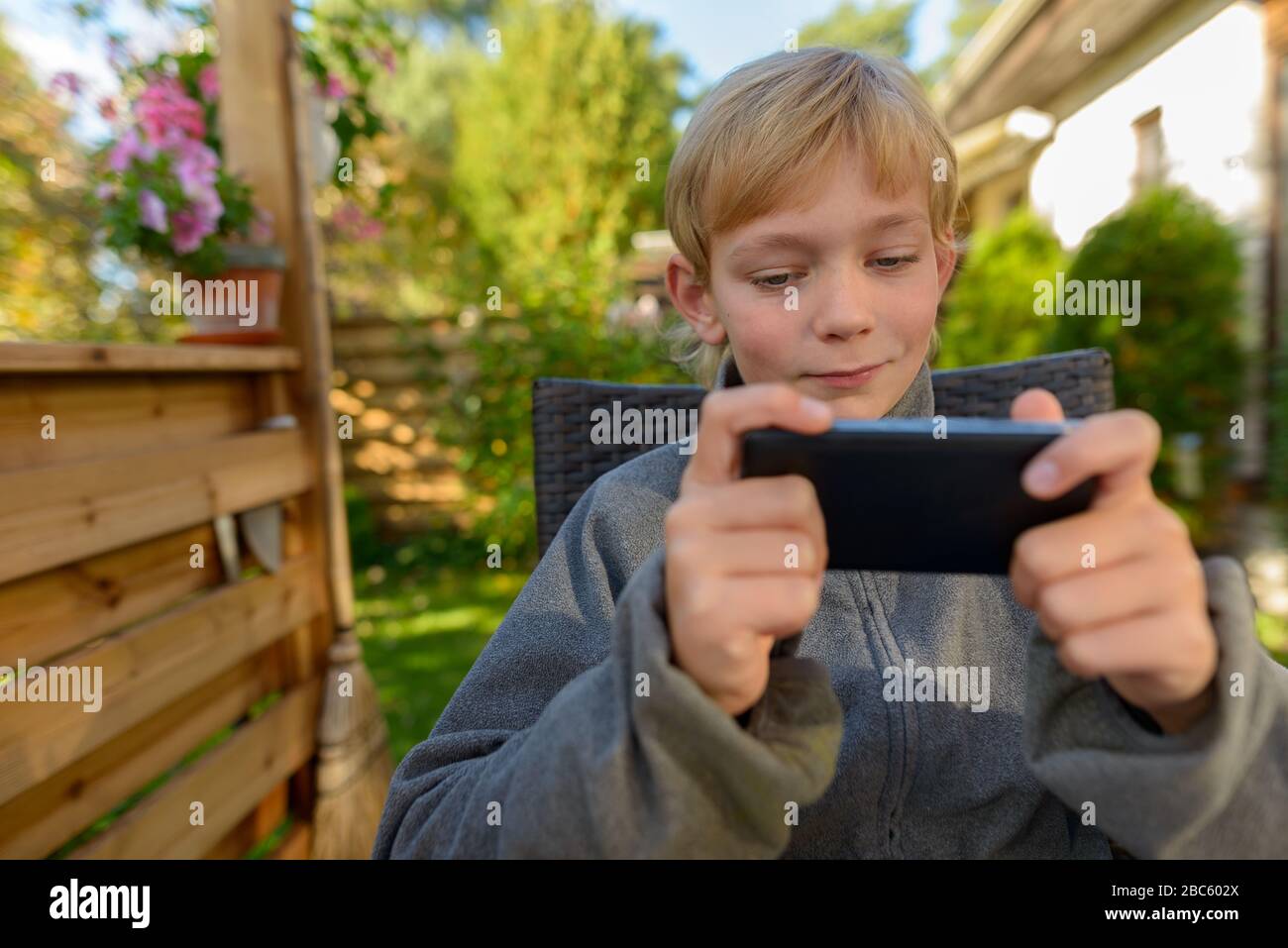 Young handsome boy using phone in the backyard Stock Photo