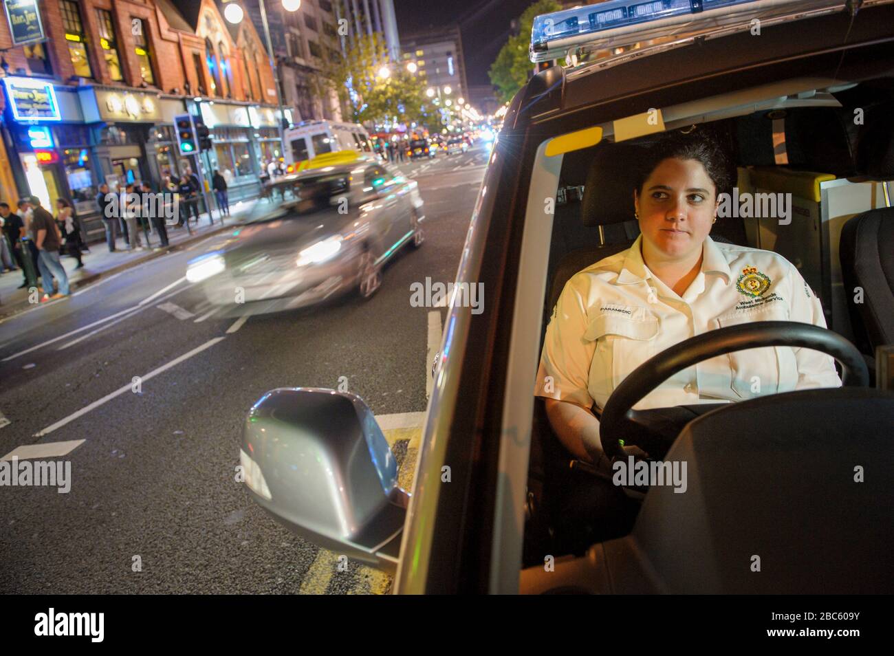 Young female Paramedic waiting in her emergency veircle Birmingham City Centre on a busy Saturday night. Stock Photo