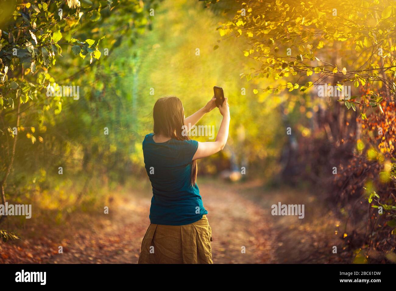 Girl taking photo using mobile phone, early autumn colors Stock Photo