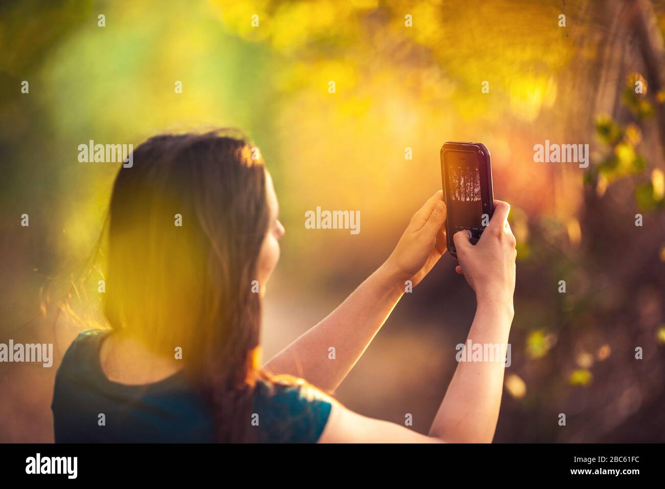 Girl taking photo using mobile phone, early autumn colors Stock Photo