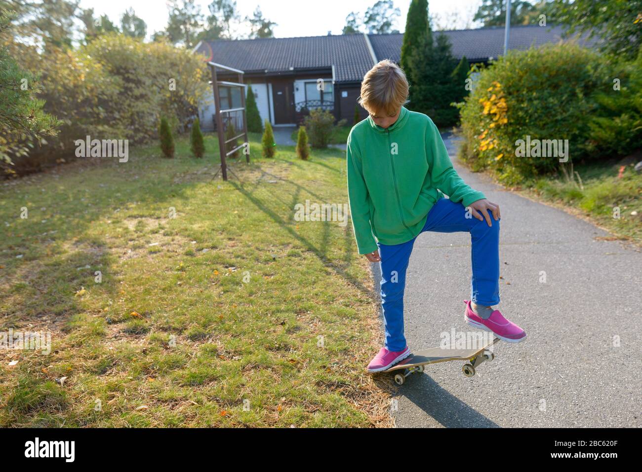 Young handsome boy skateboarding in the front yard Stock Photo