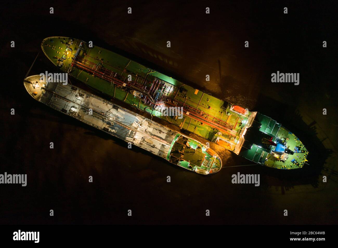 The tankers Chukotka+ and Lenaneft 2033 at night, are moored to each other, overload oil products. Stock Photo