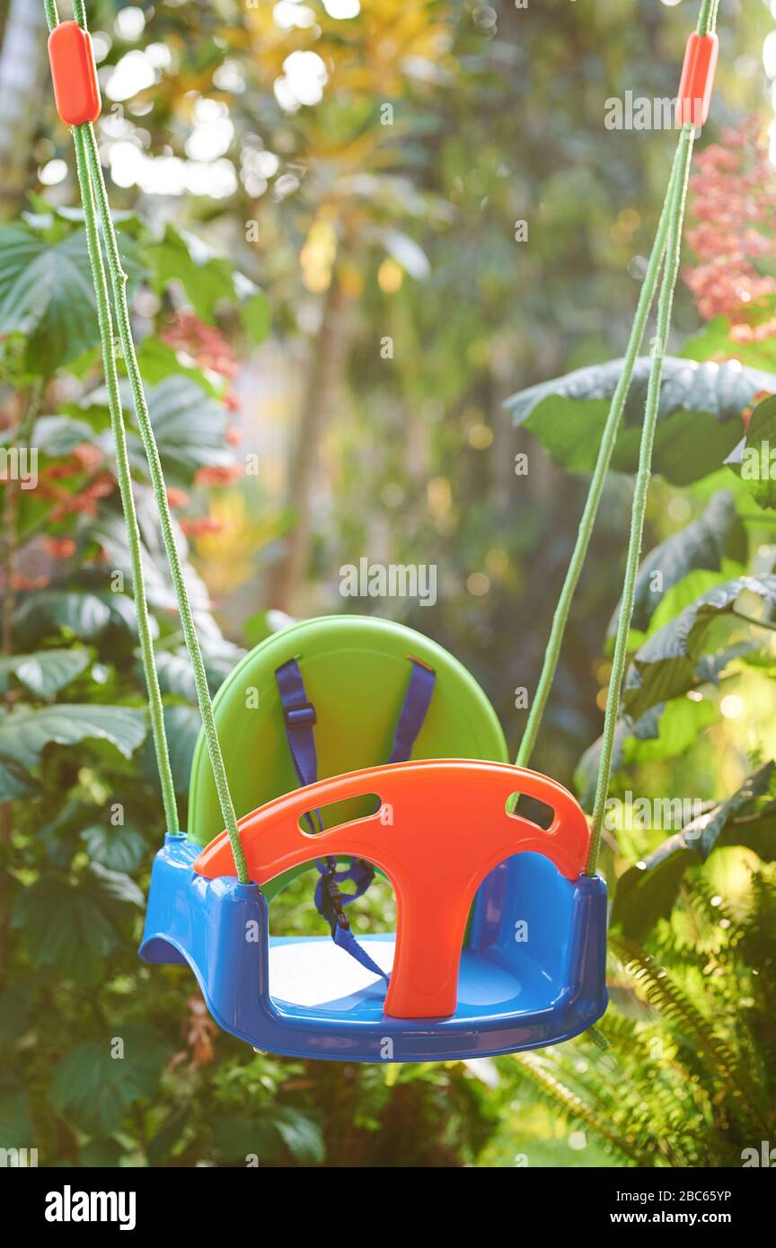 Empty kid swings on blurred green sunny background Stock Photo