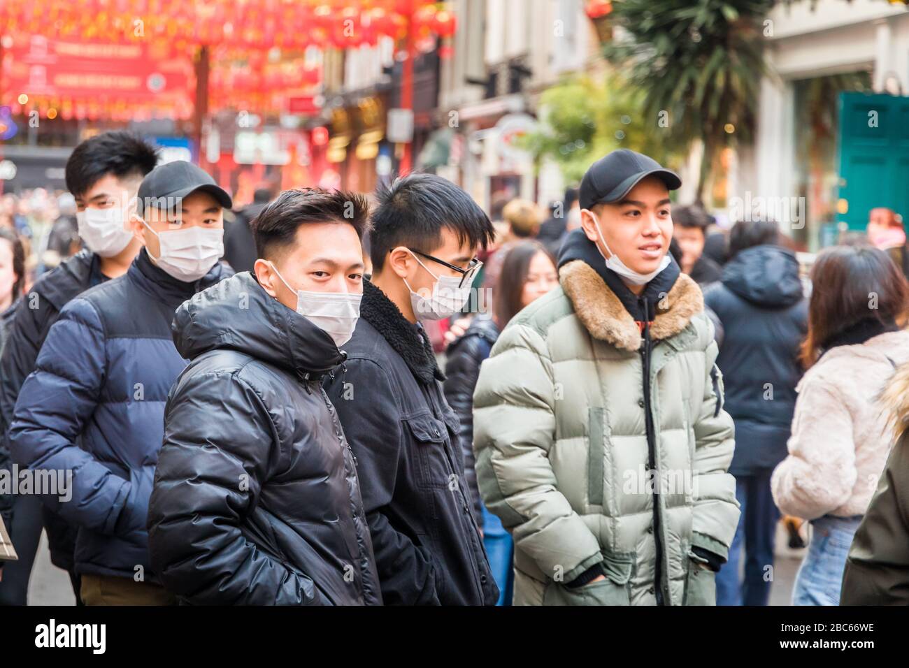 Young asian / oriental men wearing face masks, at 2020 Chinese new year celebrations in Chinatown, London, following reports of coronavirus outbreak Stock Photo