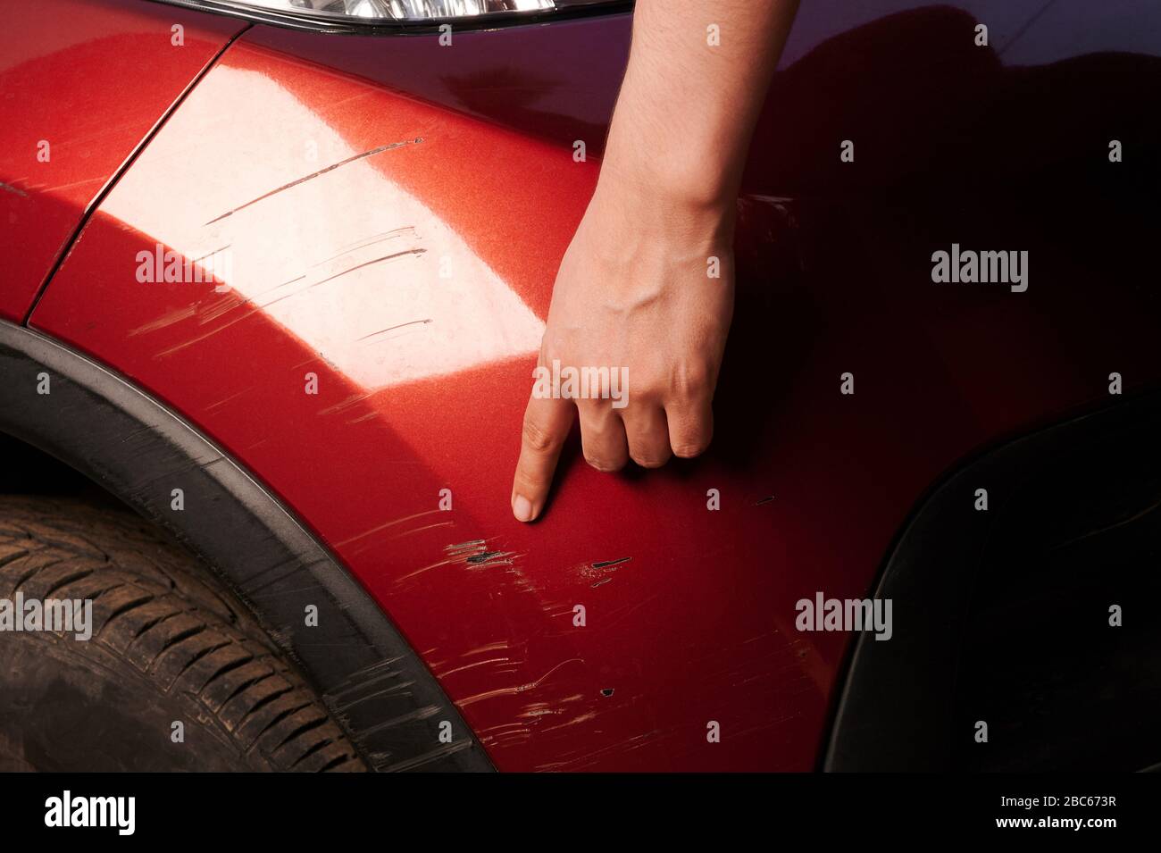 Man point on car scratch in red bumper close up view Stock Photo