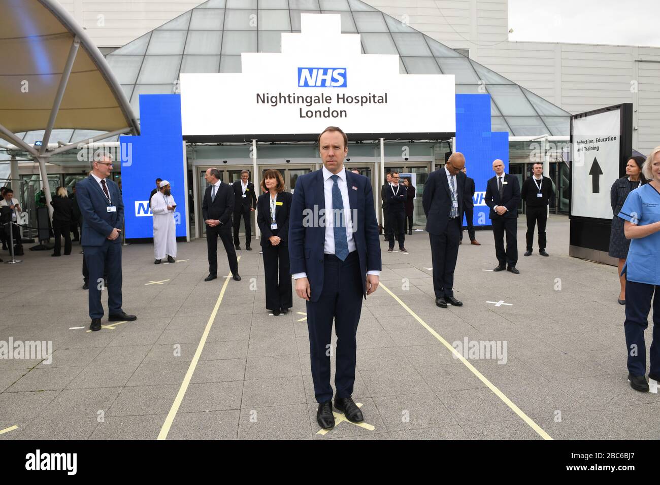 Health Secretary Matt Hancock and NHS staff stand on marks on the ground, put in place to ensure social distancing guidelines are adhered to, at the opening of the NHS Nightingale Hospital at the ExCel centre in London, a temporary hospital with 4000 beds which has been set up for the treatment of Covid-19 patients. Stock Photo