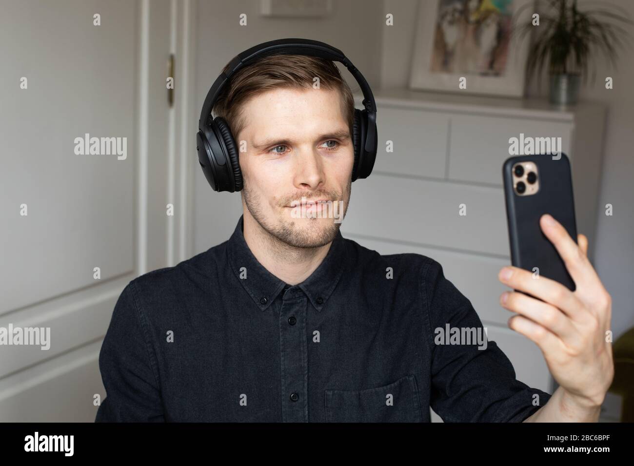 Young man having video conferencing call via smartphone. Home office. Stay at home and work from home concept during Coronavirus pandemic Stock Photo