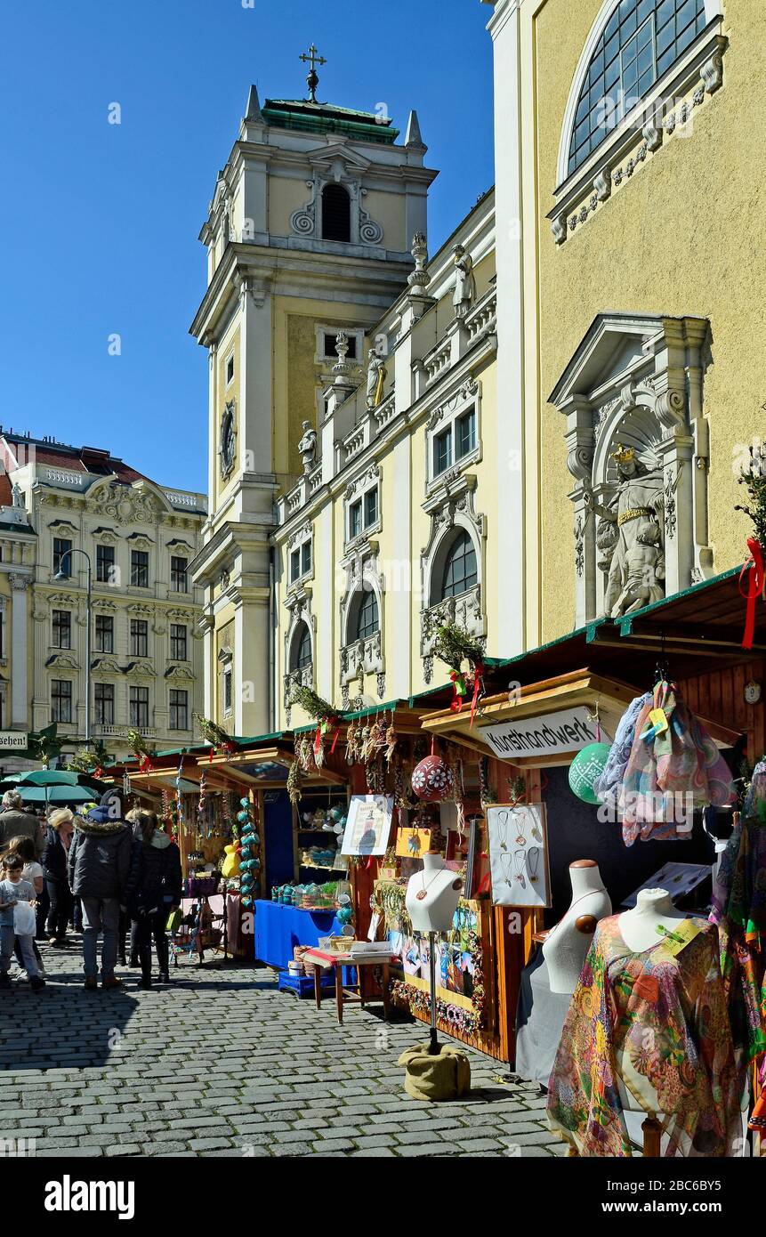 Vienna, Austria - March 27th 2016: Unidentified people and kiosks on traditional Easter market on Freyung square with church of Scottish monastery aka Stock Photo