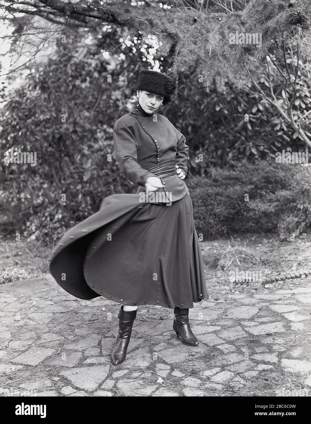 1960s, historical, a lady outside modelling the latest russian military style or 'Cossack' fashion, consisting of fur hat, high-necked top, long skirt and boots, England, UK. A group of great Russian military warriors known for their bravery, the word 'cossack' is derived from the Turkic term 'kayak' that means 'free man' or 'adventurer'. Stock Photo