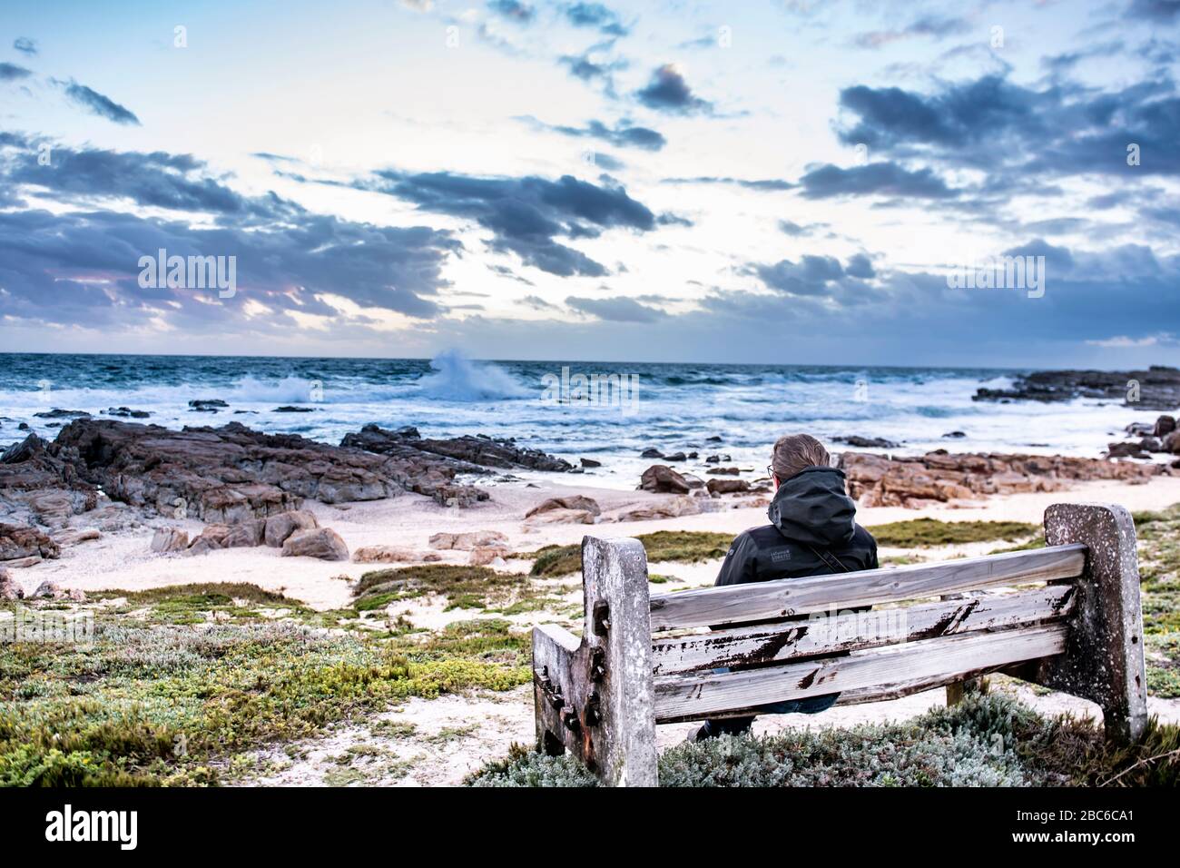 South Africa, Cape St Francis, Sun going down, over the Indian Ocean and the waves are pounding on the Rocks, while sitting there. Stock Photo