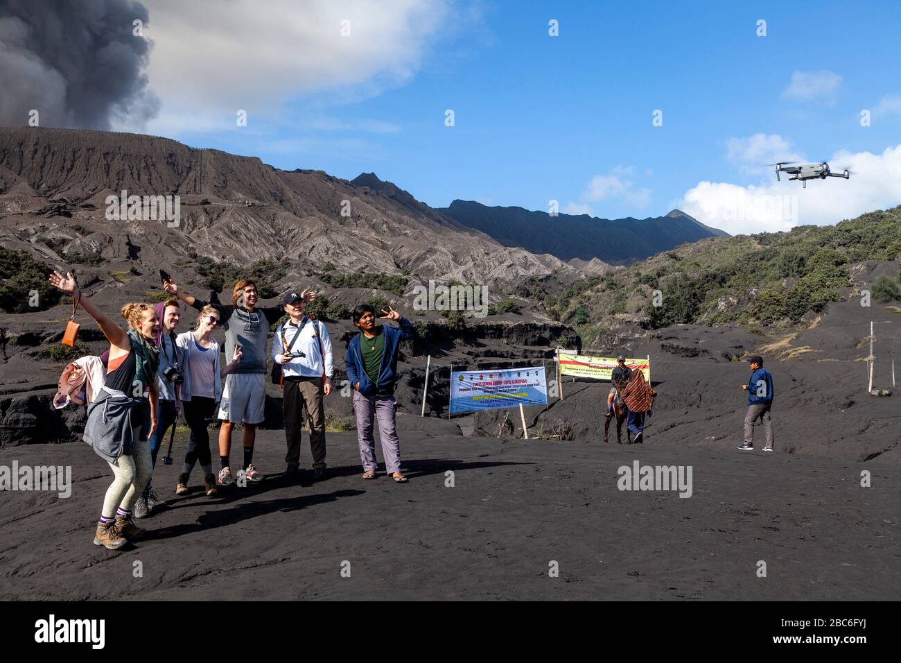 Tourists Pose For A Drone Selfie On The Sea Of Sand, In The Backround Is An Erupting Mount Bromo, Bromo Tengger Semeru National Park, Java, Indonesia Stock Photo