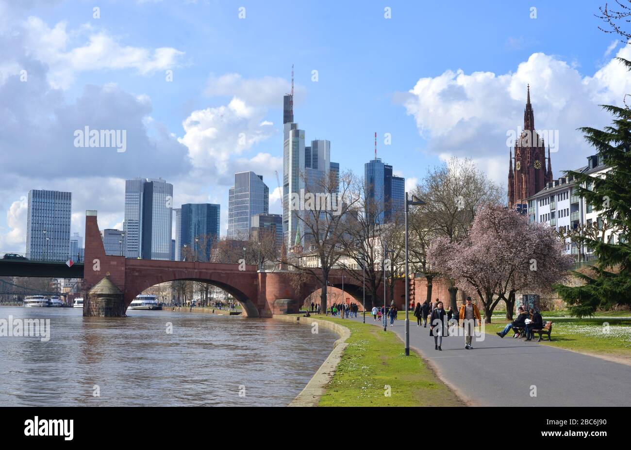 Frankfurt Main, Germany 03-14-2020 people walking on the river main with view to the downtown and the old bridge Stock Photo
