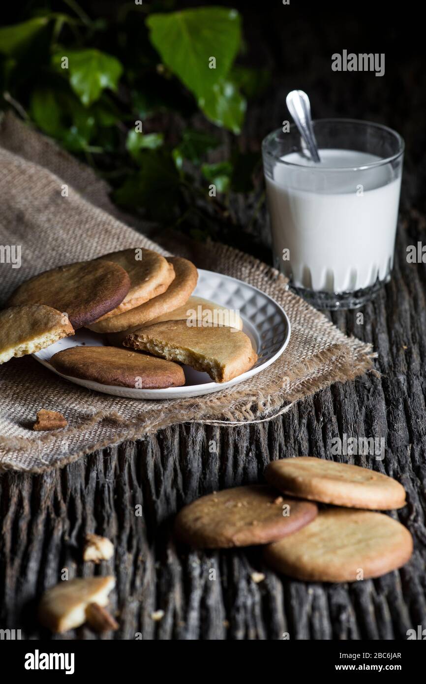 A handmade cookies on a plate on a rustic wooden board and with a glass of milk Stock Photo