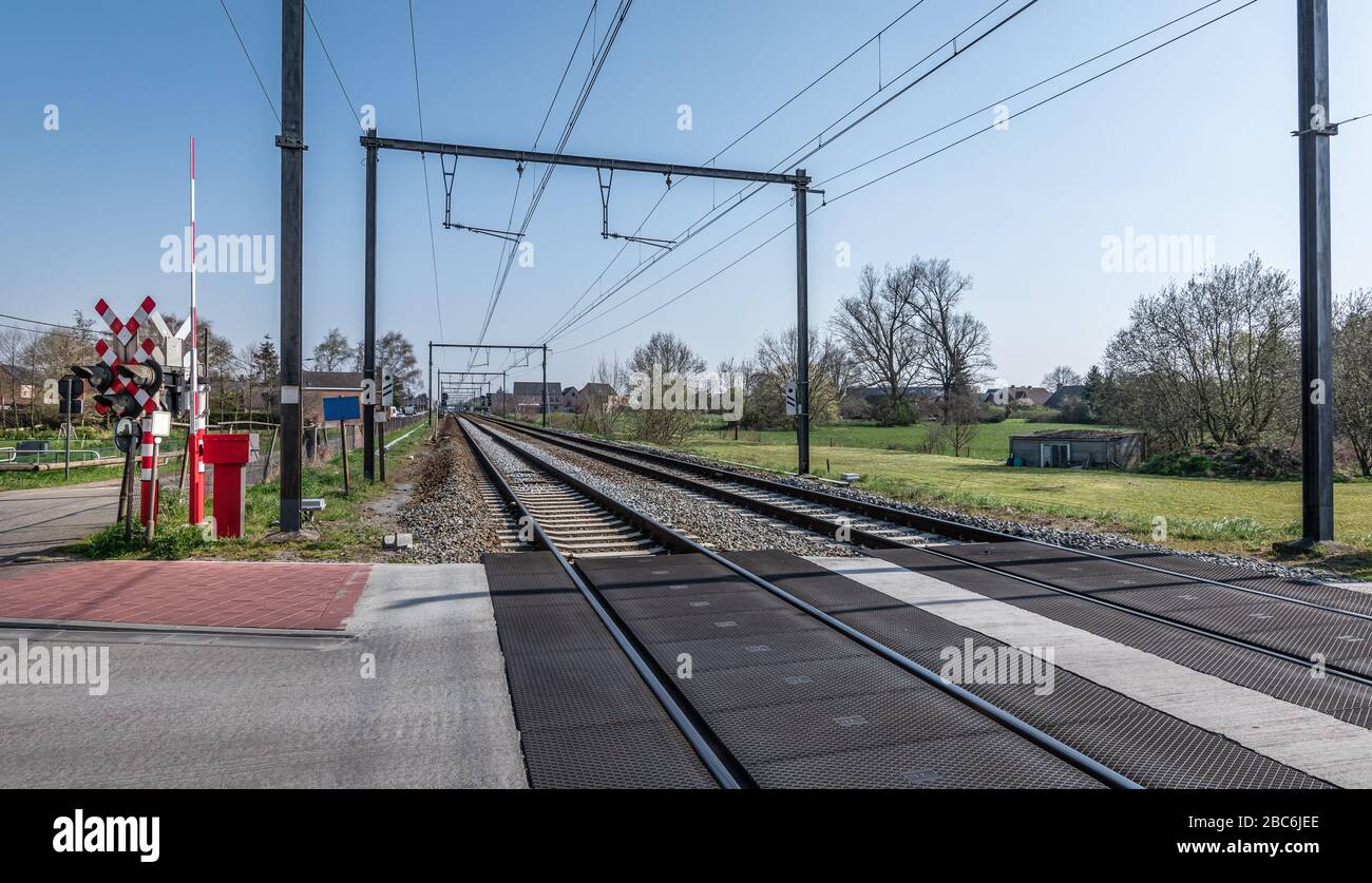 Railroad crossing in the countryside in Belgium. Railway and transportation concept. Stock Photo