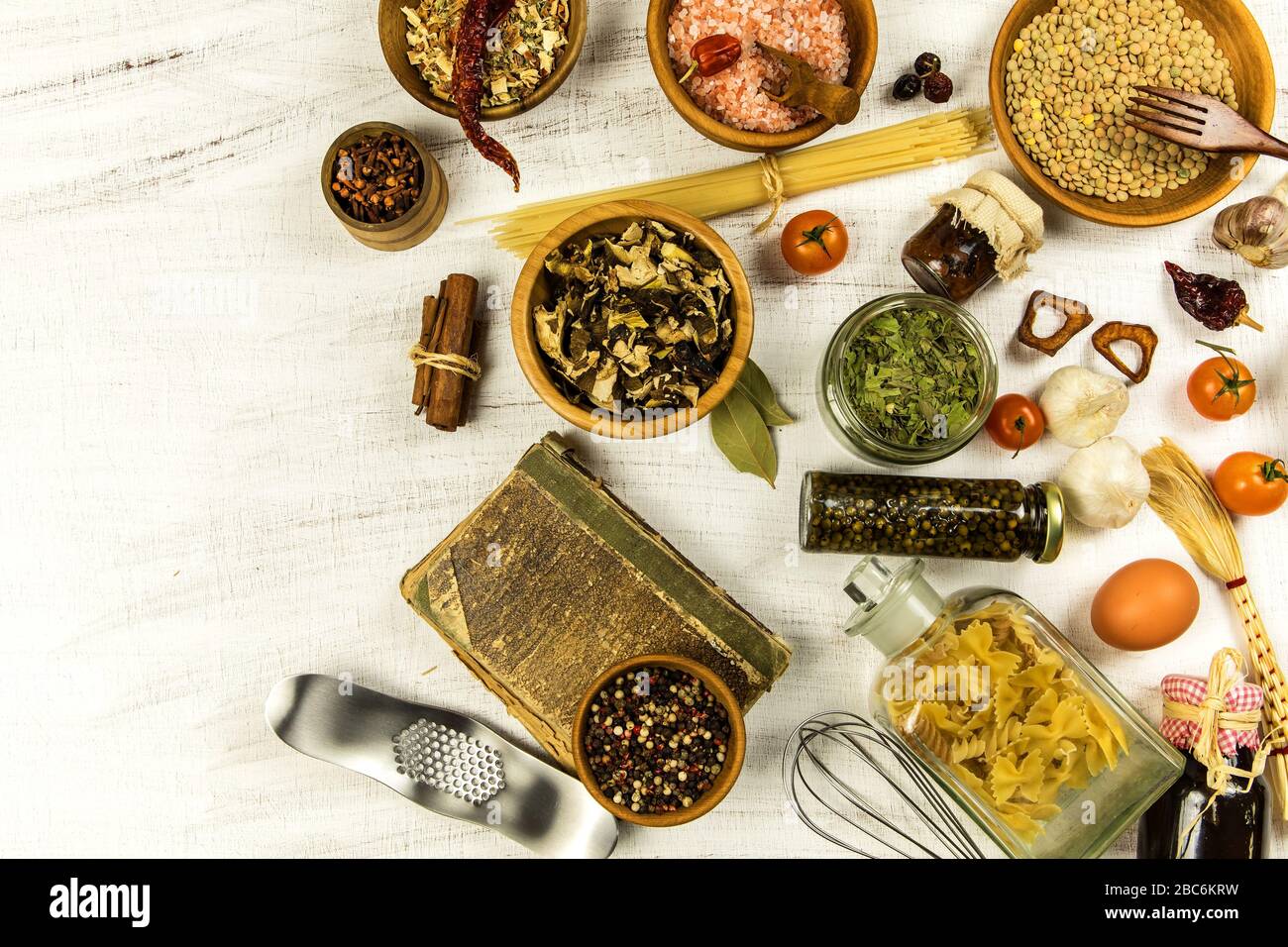 Herbs and spices with a recipe book on white wooden background. Blank ...