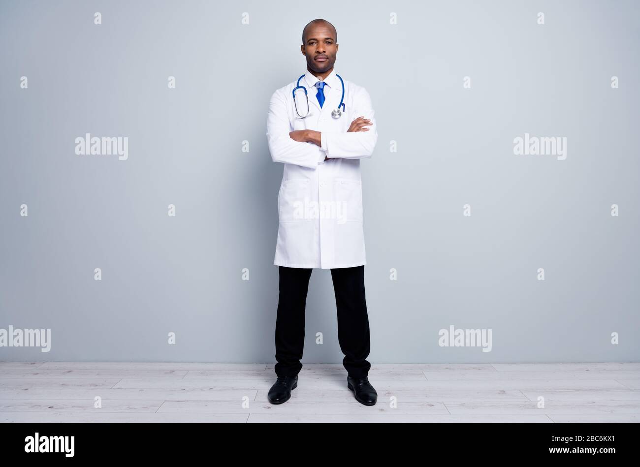 Full body photo of professional family doctor dark skin guy meet patients virologist arms crossed wear white long lab coat neck tie pants shoes Stock Photo