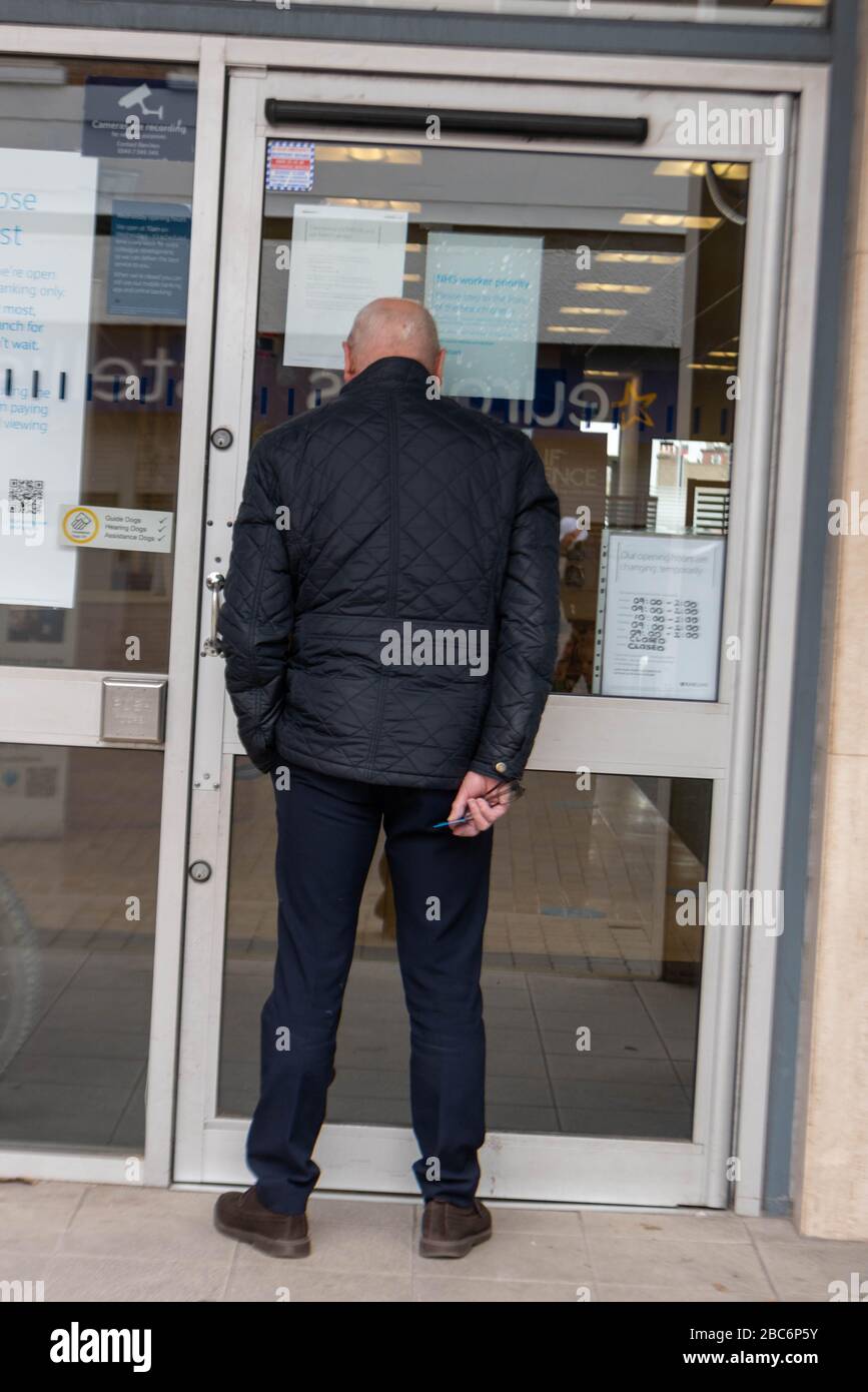 Brentwood Essex, UK. 3rd Apr, 2020. Larger numbers of cars and pedestrians in Brentwood High Street. during the covid lockdown. In particular large lines outside retail banks A man waits outside a bank Credit: Ian Davidson/Alamy Live News Stock Photo