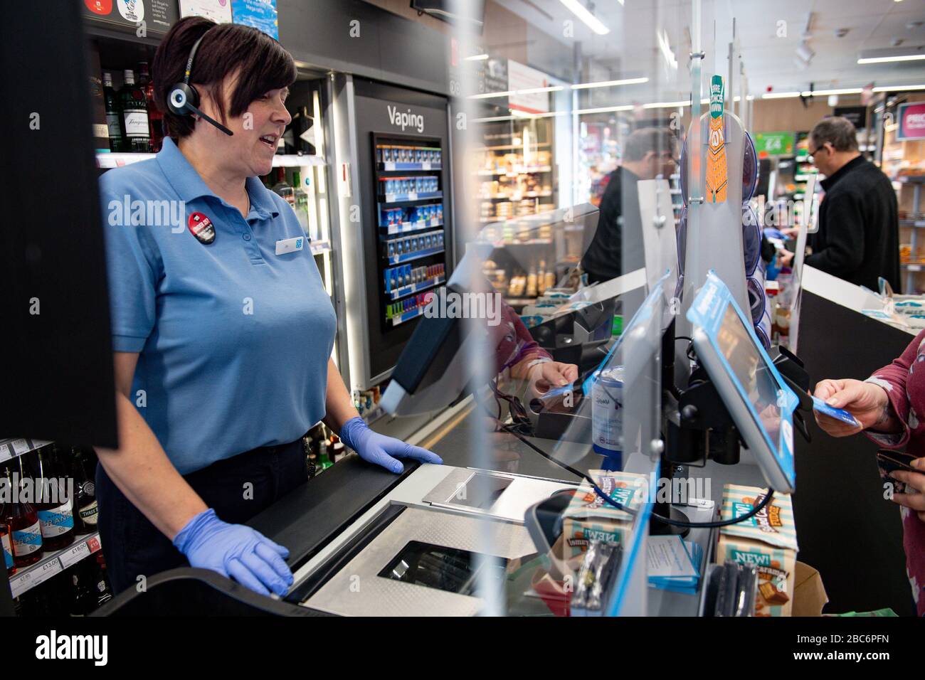 A clear screen divides employees and customers at a Co-op shop in Bromsgrove, Worcestershire. Stock Photo