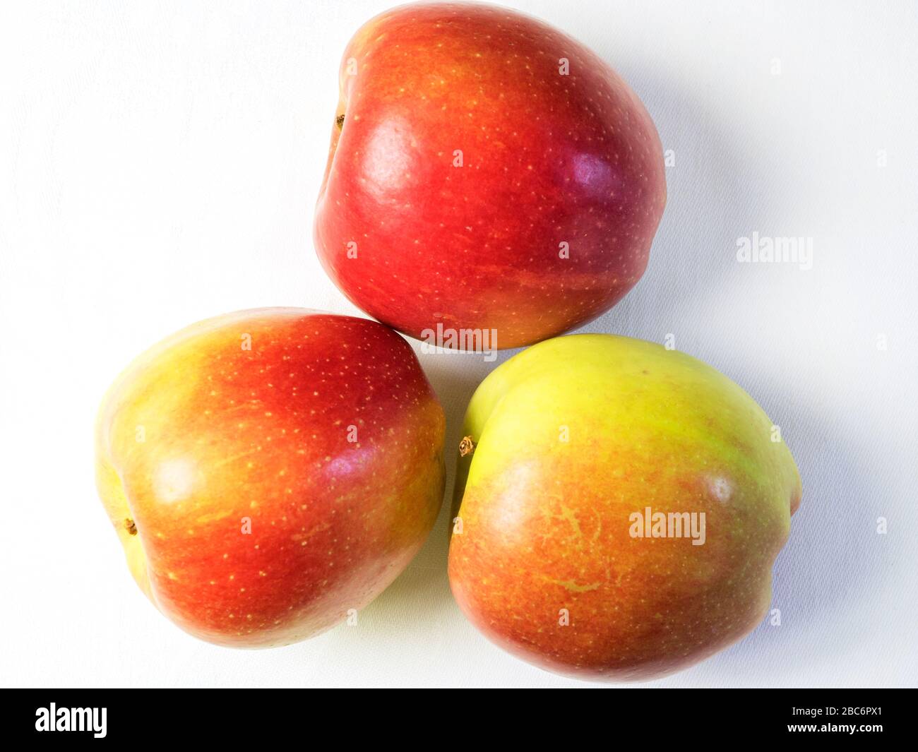 Three braeburn apples from above on a white tablecloth Stock Photo