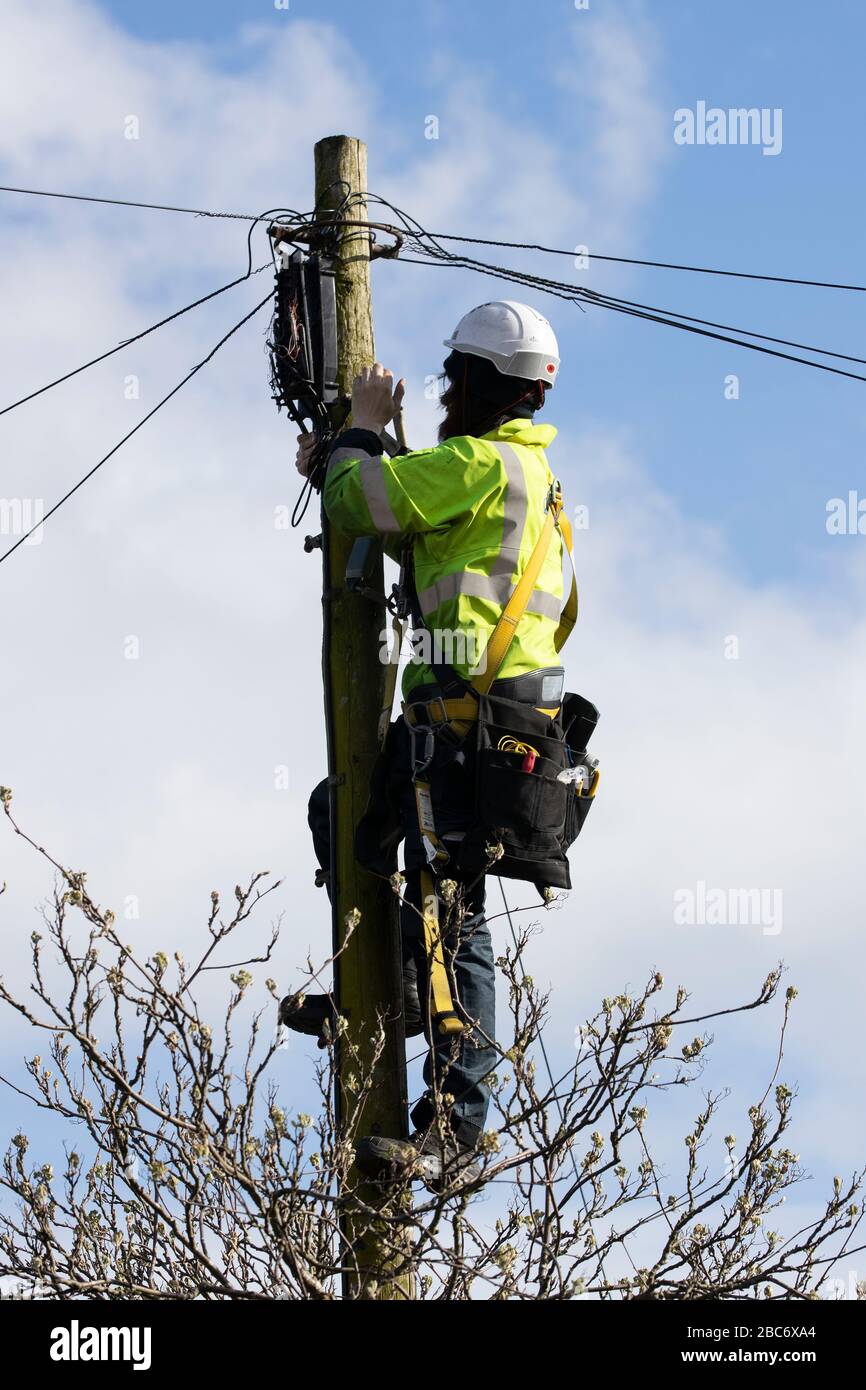 field engineer climbing a telegraph pole and carrying out