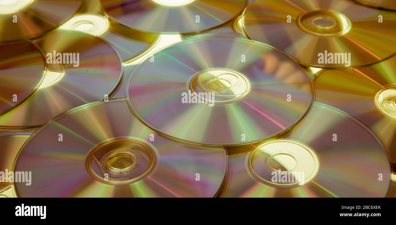 Yellow compact discs background warm Cd Dvd Blue ray laid out on a flat surface Stock Photo
