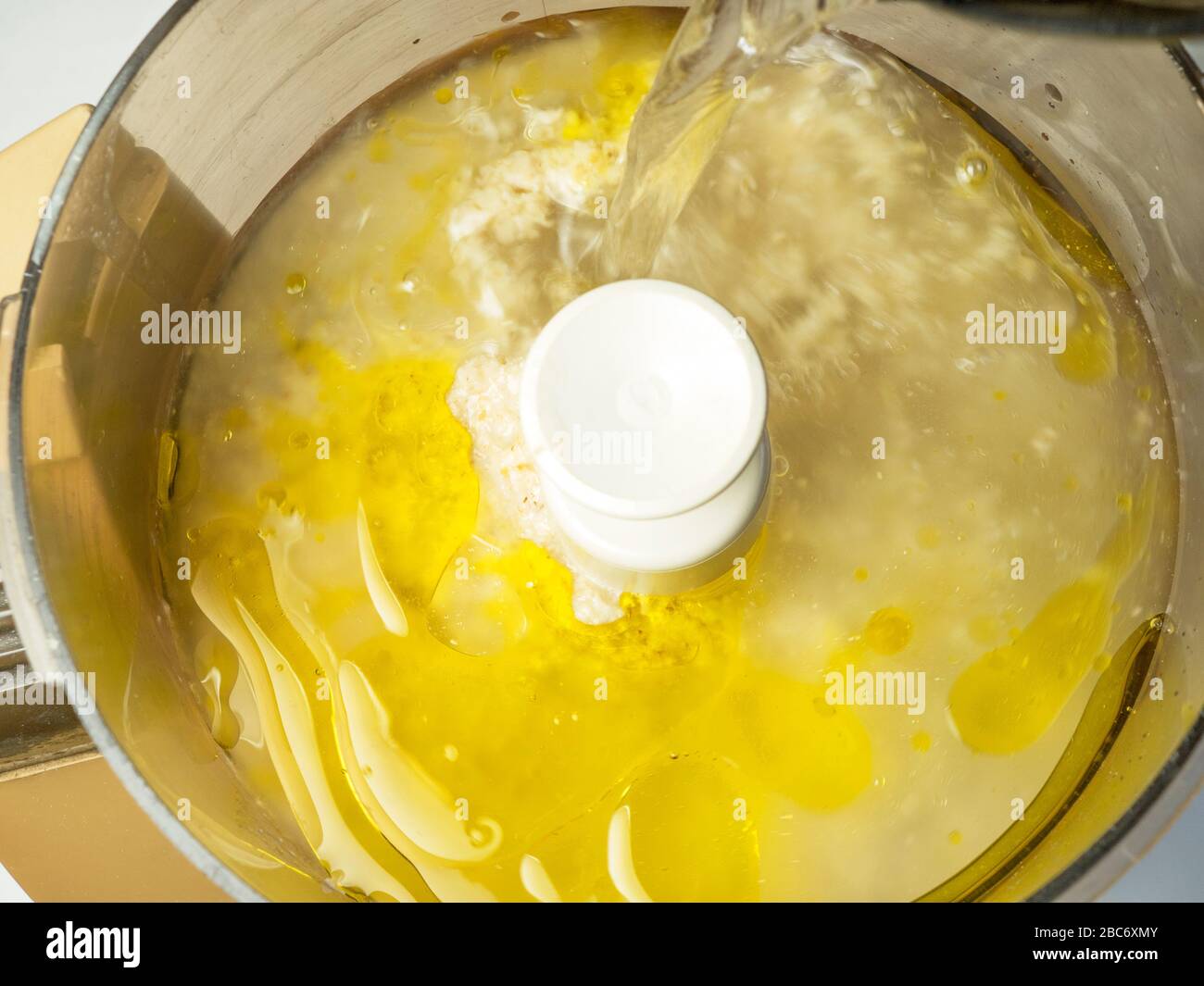 Adding water to soaked rolled oats and rapeseed oil with a pinch of sea salt in a food processor ready for making dairy alternative oat cream Stock Photo