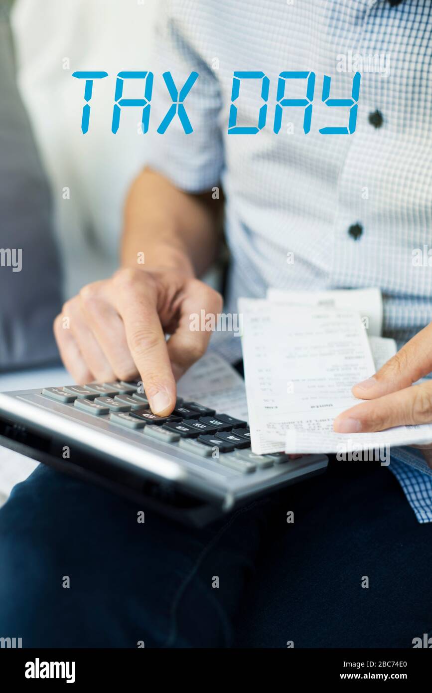 closeup of a caucasian man, with a pile of bills and tickets in his hand, using an electronic calculator and the text tax day Stock Photo