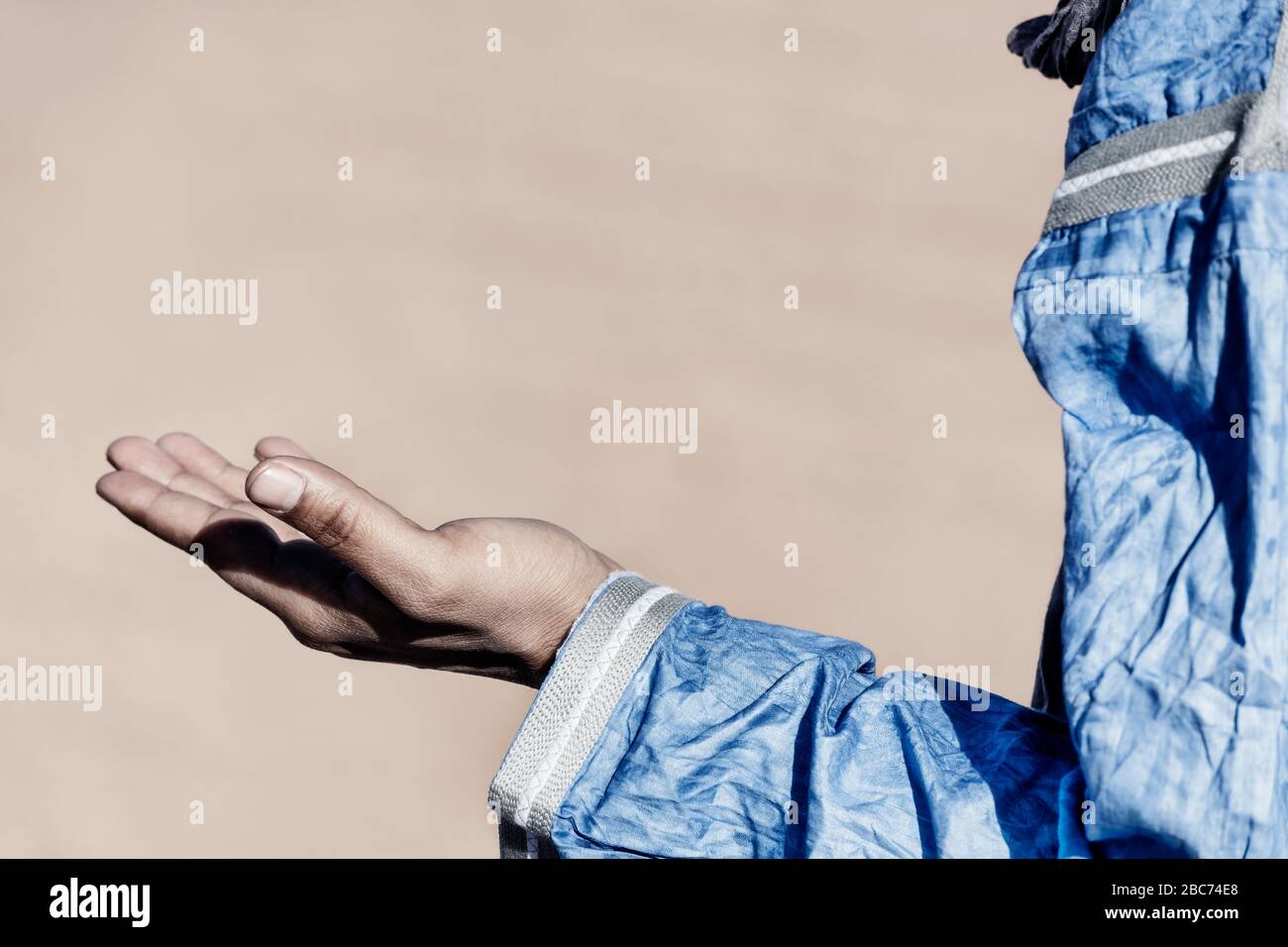 Open hand of a traditional dressed Moroccan man. High key image with muted colors. Stock Photo
