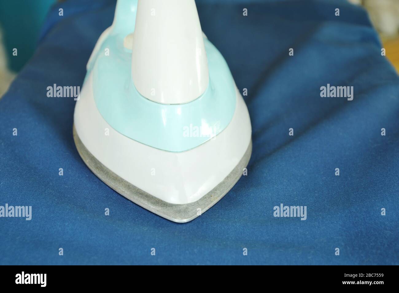 blue automatic electric iron pressing cloth on ironing board Stock