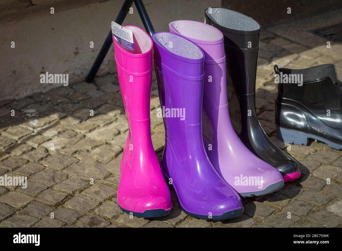 Five colorful pairs of rubber boots in pink, purple, violet and black Stock Photo