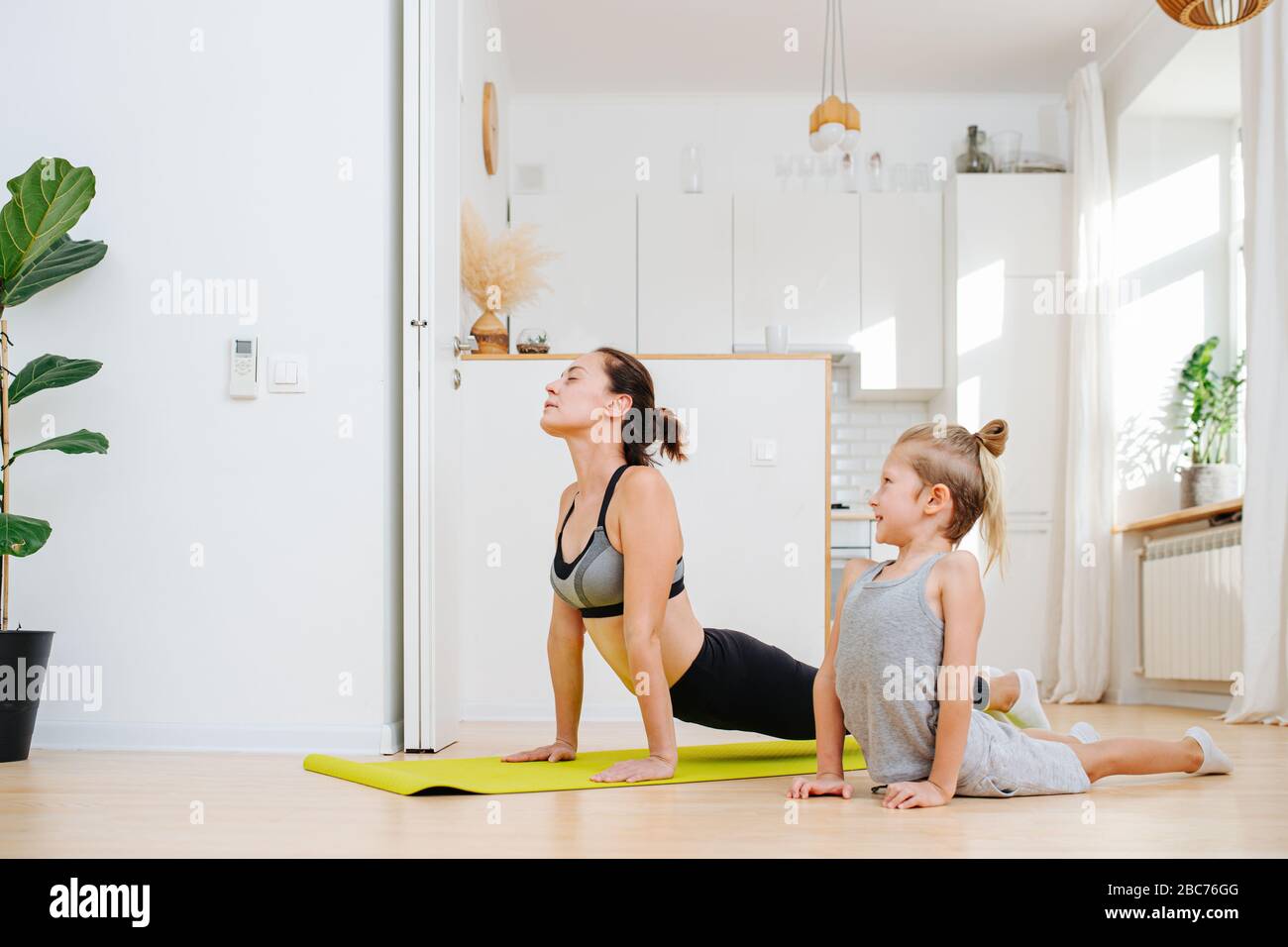 Mom and son doing yoga, pushing with arms, bending thier backs Stock Photo