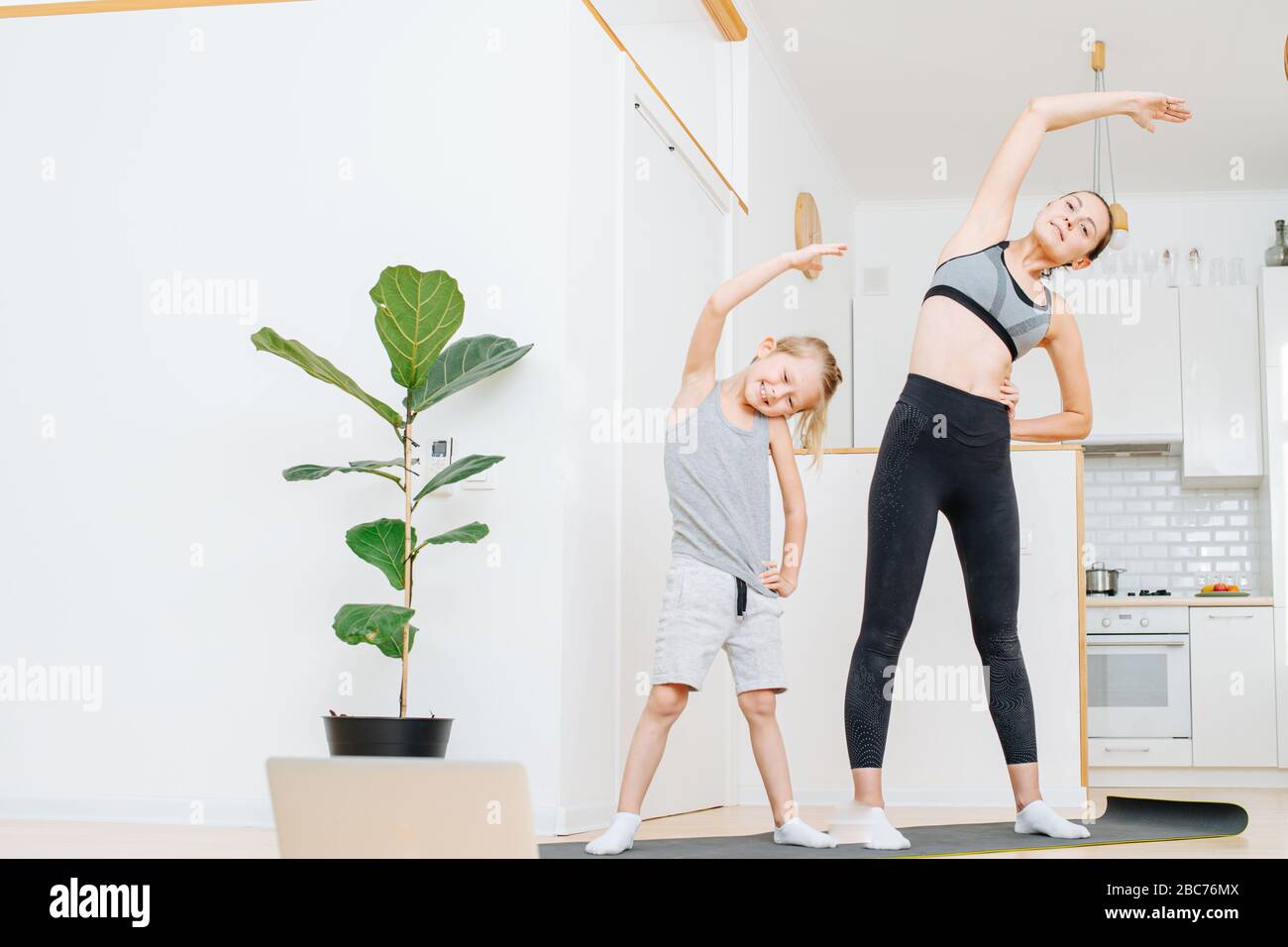 Smiling mother and son doing side bends exercise, keeping fit Stock Photo