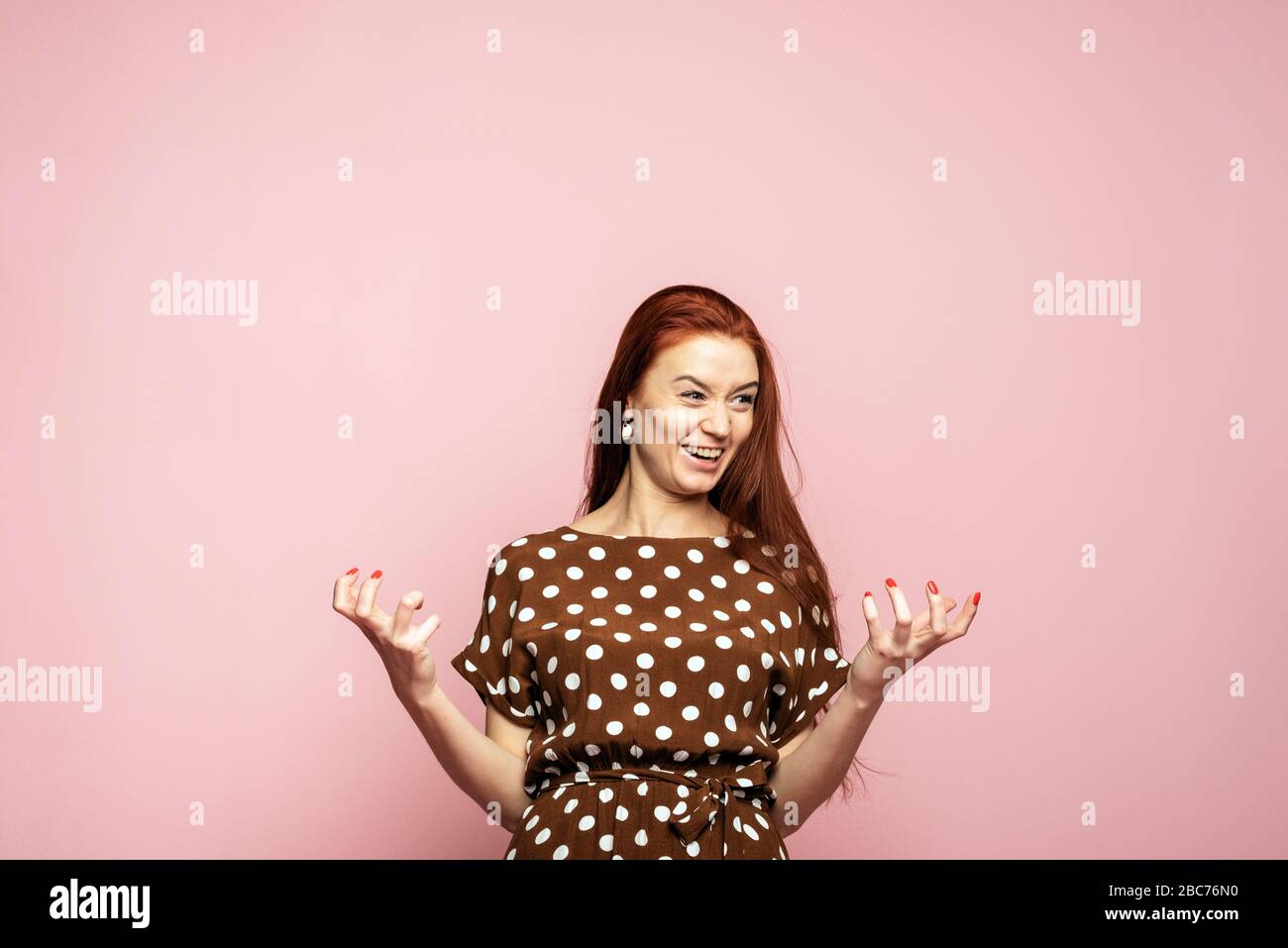 A sweet and beautiful woman experiences a strong emotion of joy and happiness. Beautiful girl on a pink background rejoices. Template for your advertisement. Stock Photo