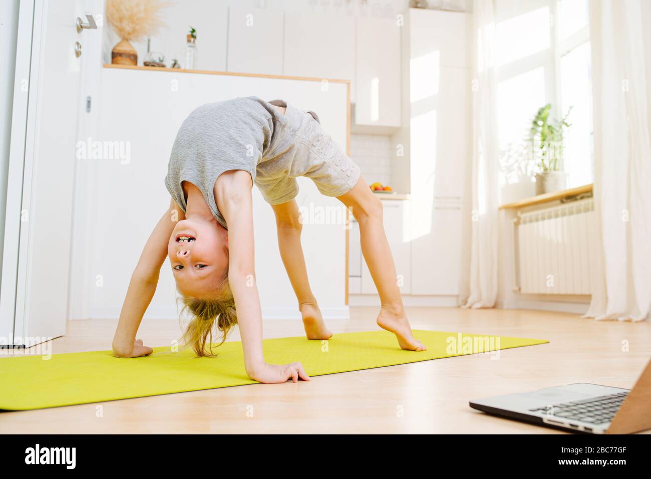 Little boy doing full bridge exercise, looking at camera. On isolation at home. Stock Photo