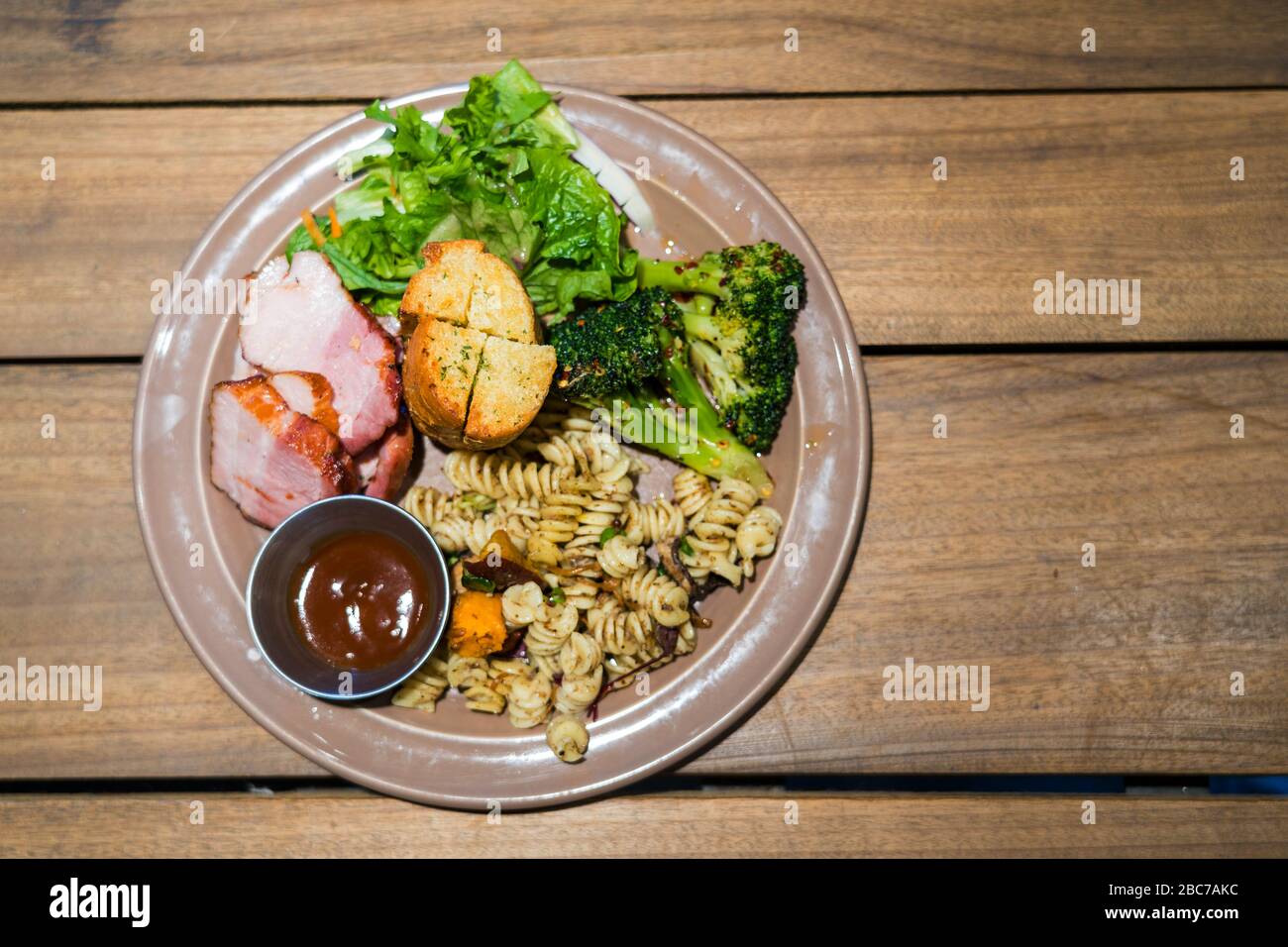 Top view image of healthy diet food. Grilled fusilli pasta and broccoli, meat, garlic bread, vegetables on a plate. Stock Photo