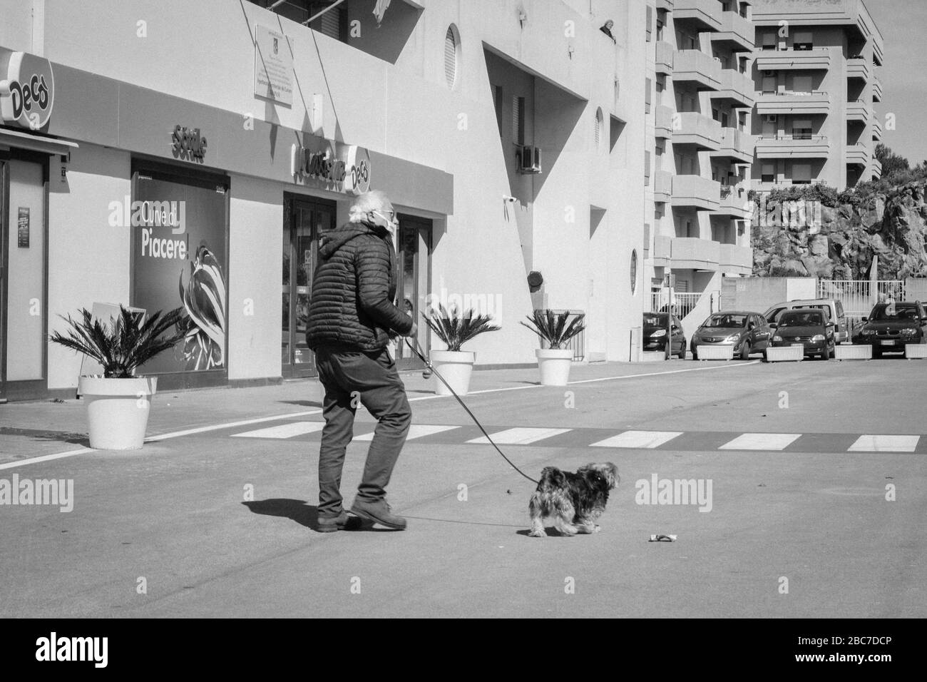 Man wearing mask walking with dog during quarantine Stock Photo