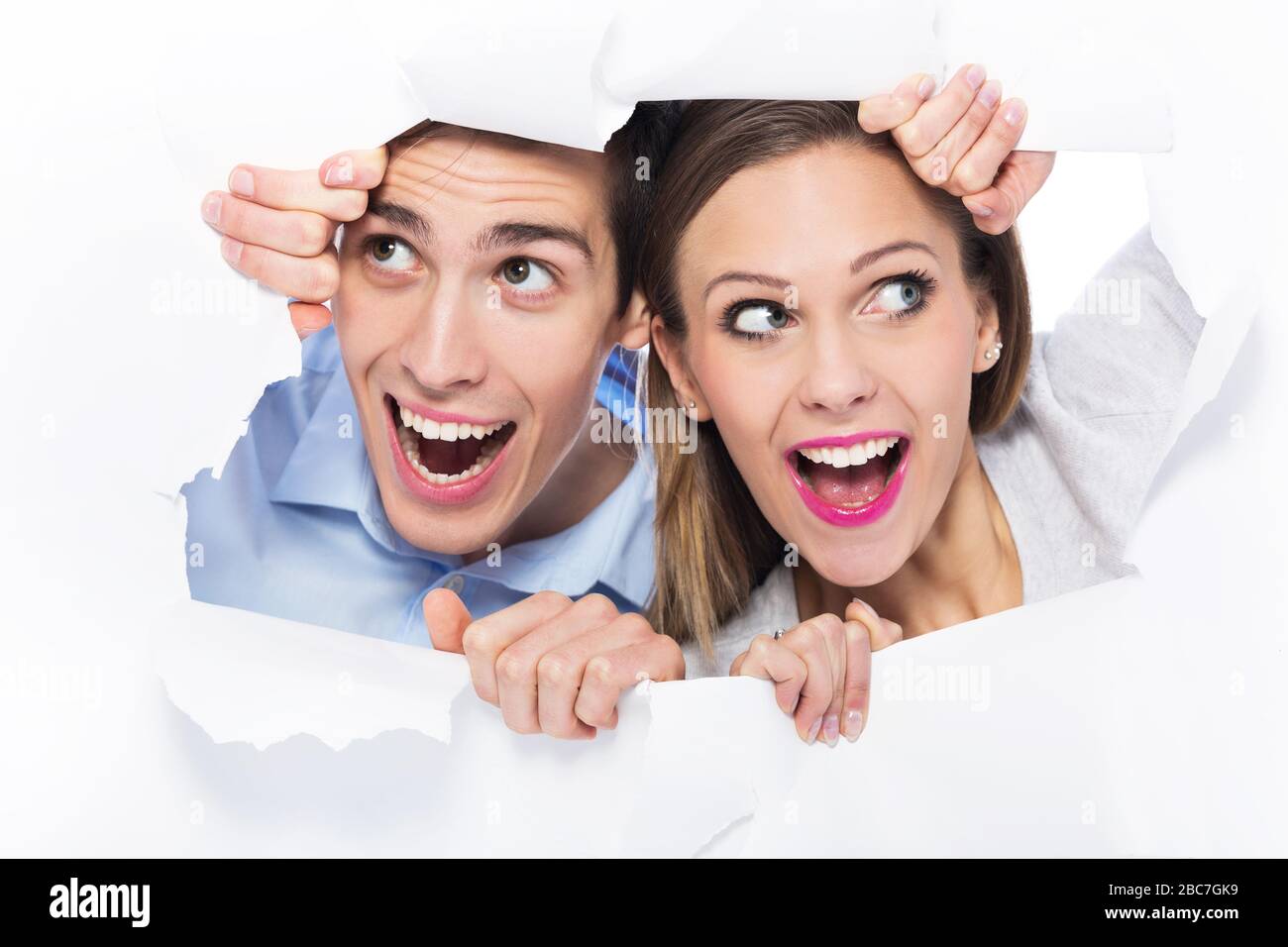 Couple peeping through hole on paper Stock Photo