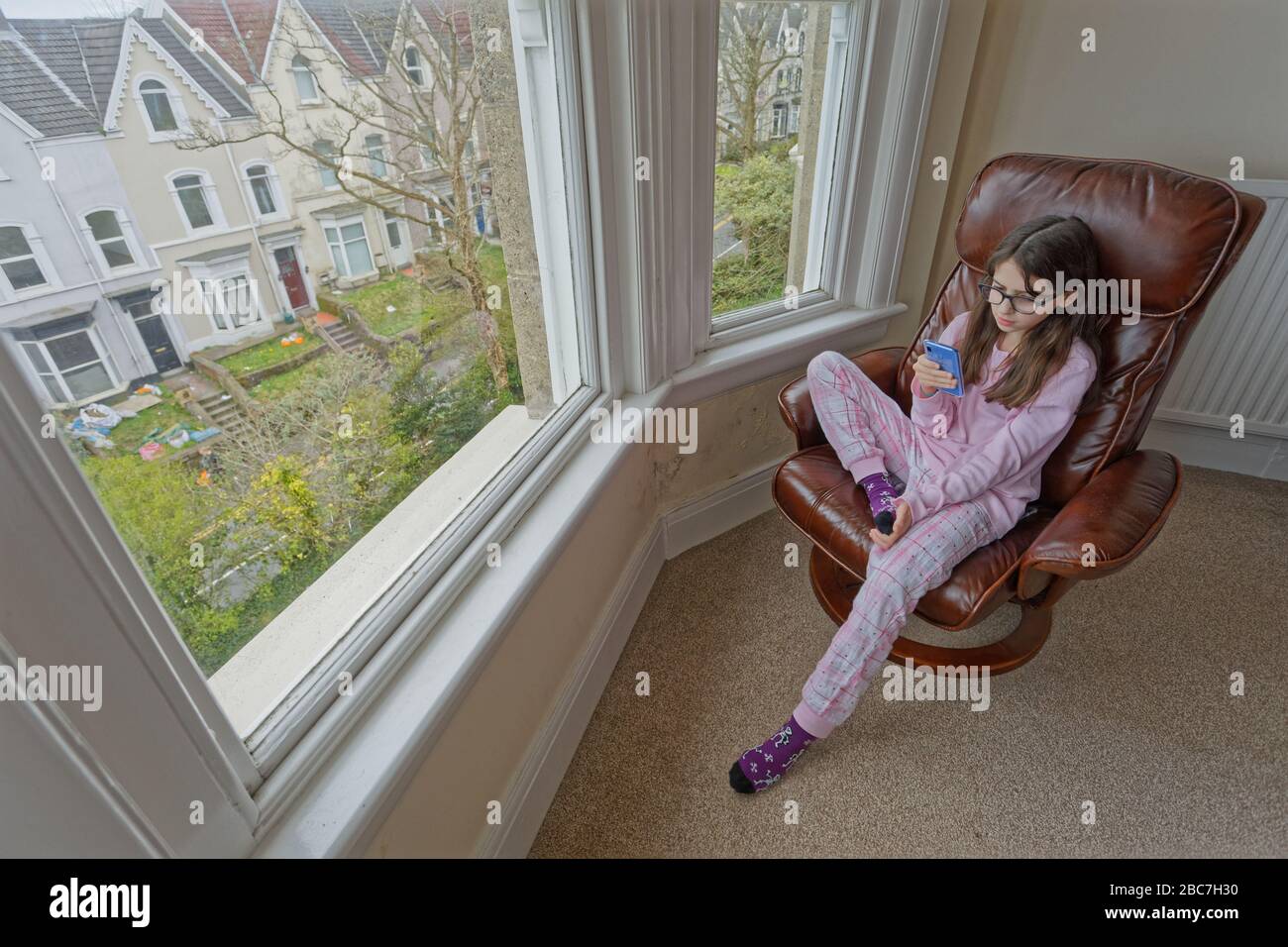 Sophie Rhian, 11, spends time on her mobile phone speaking to friends while self-isolating with her family in Swansea Stock Photo