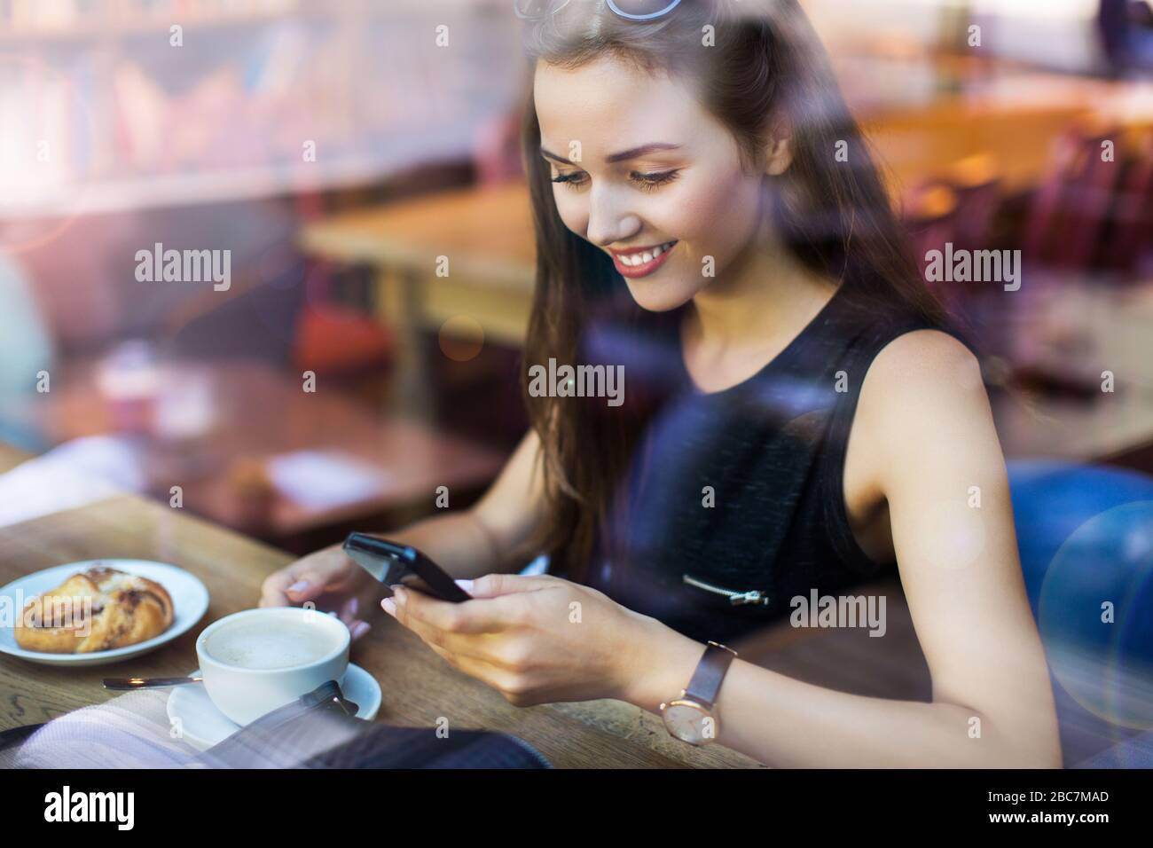 Young woman seen through cafe window Stock Photo