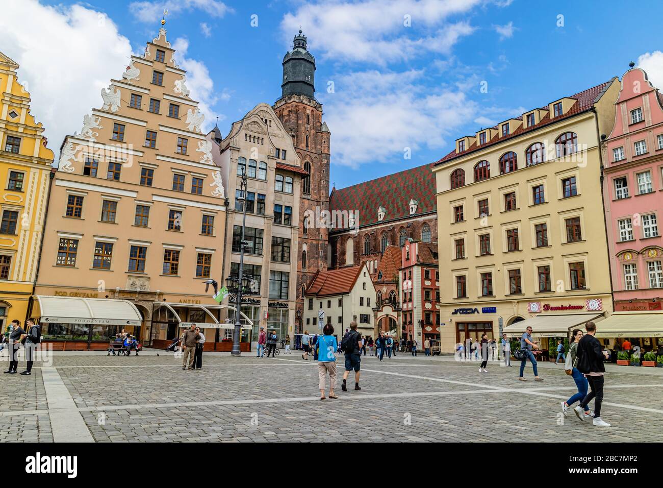 People in Wroclaw's main square, the rynek, with landmarks St Elizabeth's Church and the Hansel & Gretal houses behind. Wroclaw, Poland. July 2017. Stock Photo
