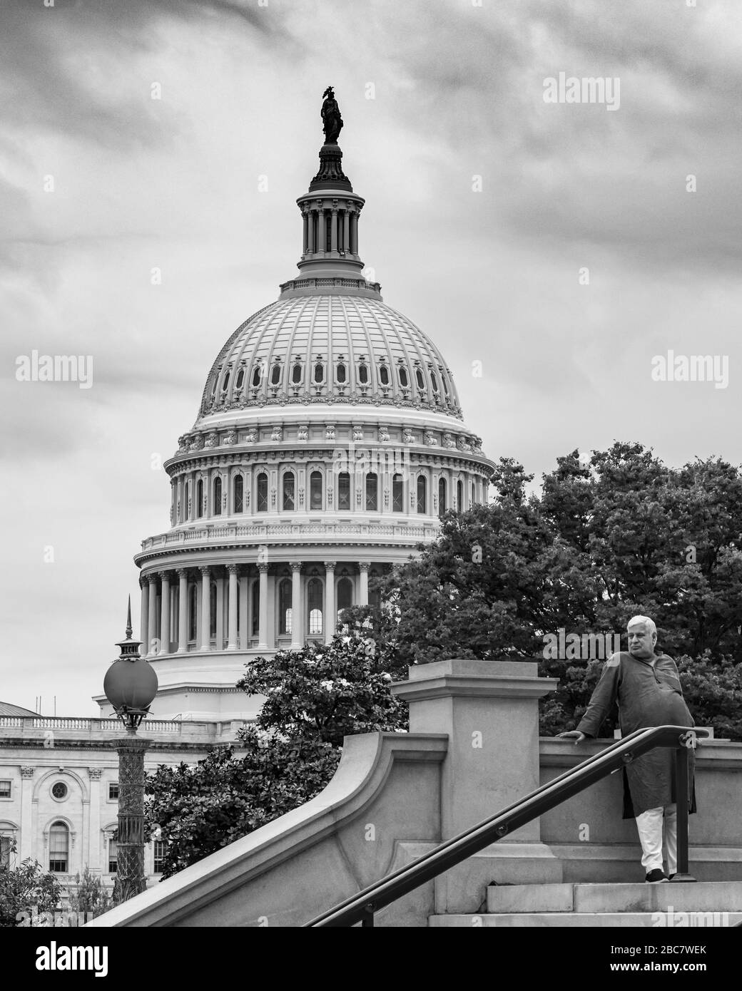 A man in shalwar Kameez stands on the steps of the Library of Congress with the white dome of the US Capitol building as a backdrop. Stock Photo