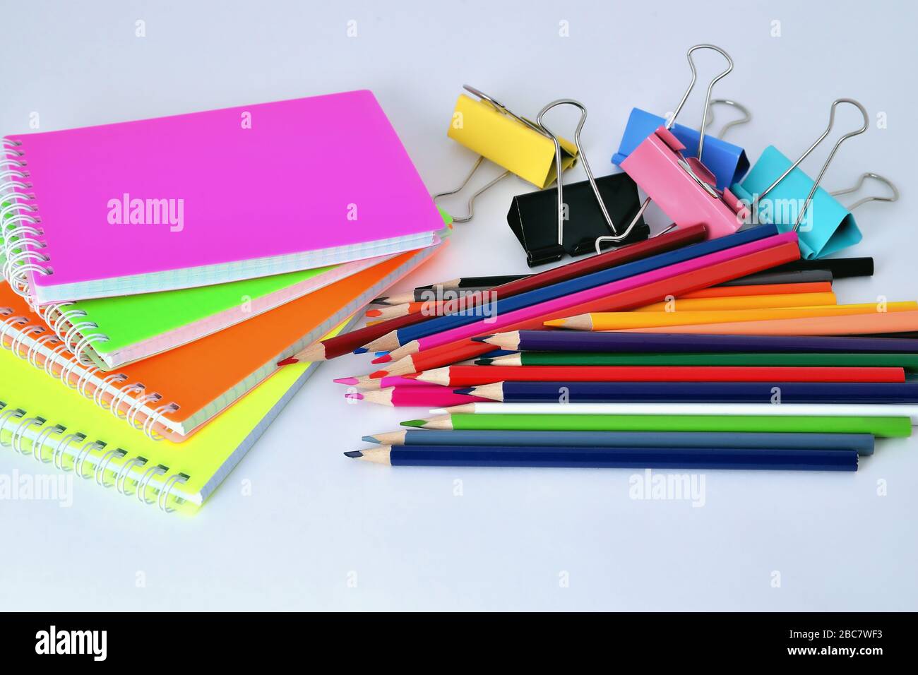 Color pads, pencils and paper clips on white background Stock Photo