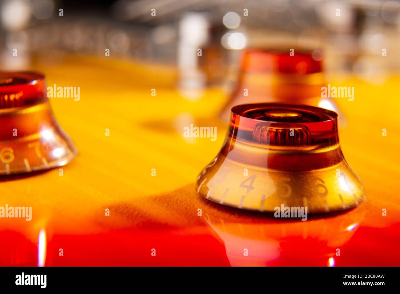 selective focus on the amber knob located on the top of a flamed cherry colored electric guitar Stock Photo