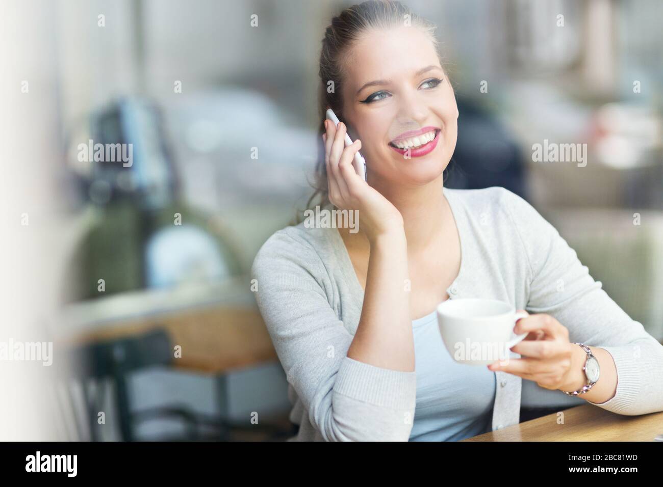Woman using mobile phone at cafe Stock Photo