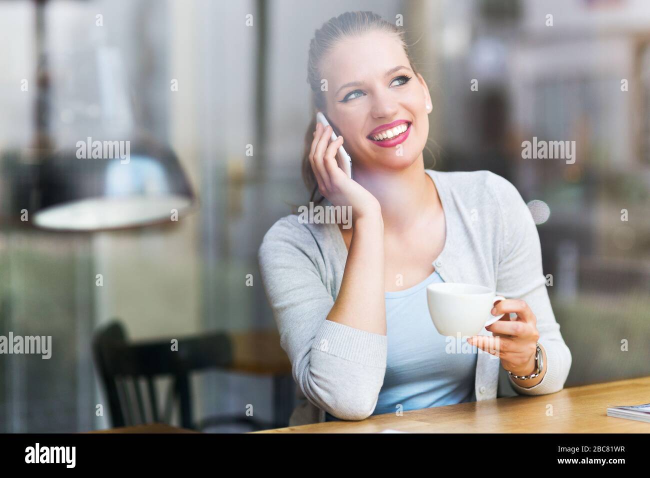 Woman using mobile phone at cafe Stock Photo
