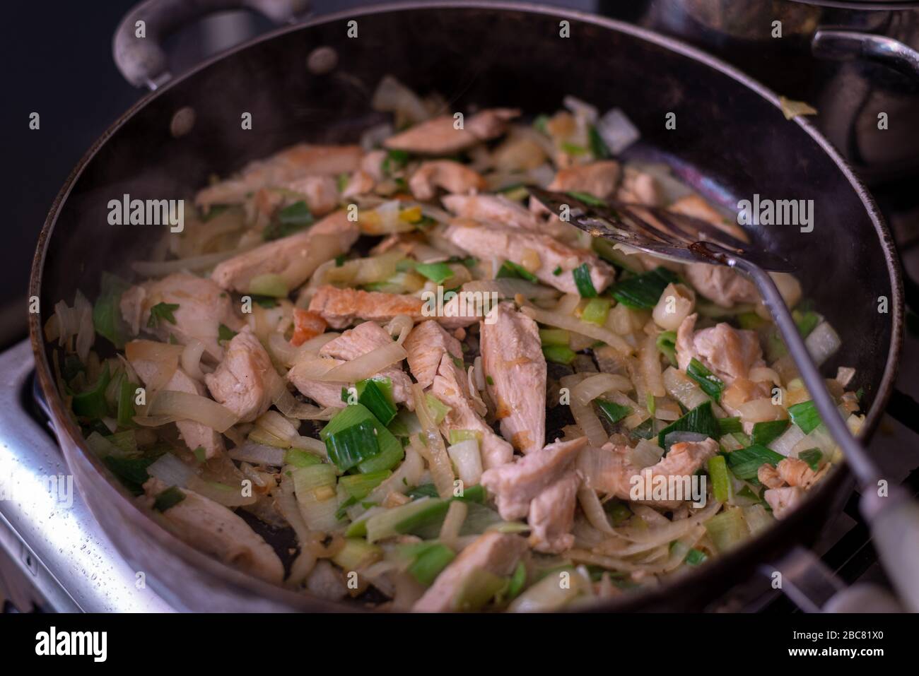 Cooking a chicken curry while stuck at home.chicken & vegtables in large frying pan. Stock Photo