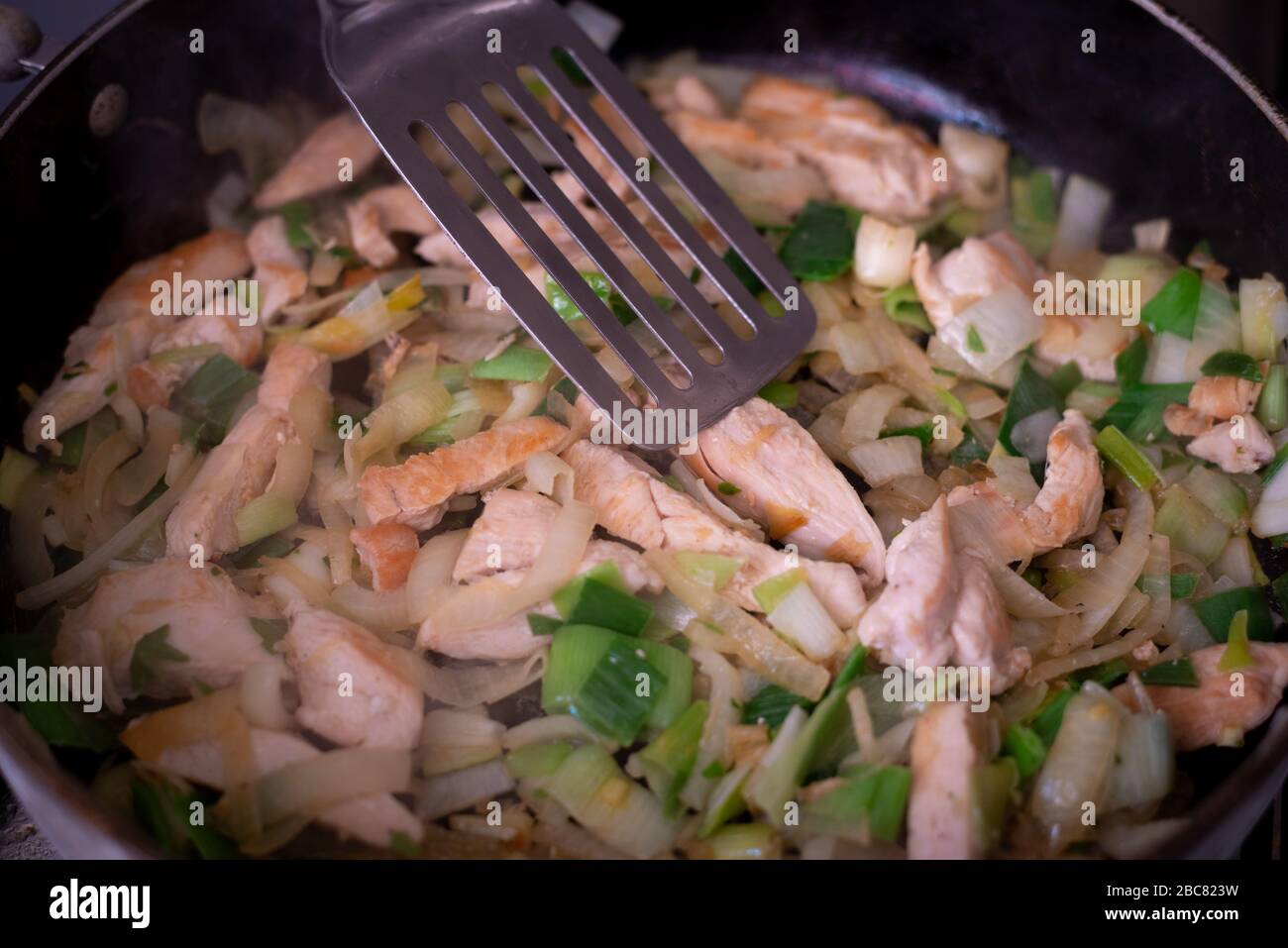 Cooking a chicken curry while stuck at home.chicken & vegtables in large frying pan. Stock Photo