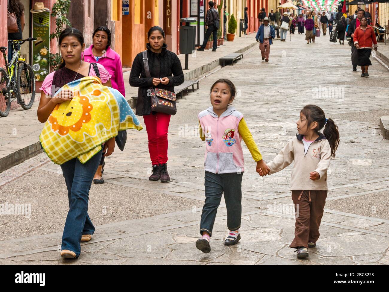 Maya mother carrying an infant, two young daughters, at Calle Real de Guadalupe, pedestrian street in San Cristobal de las Casas, Chiapas, Mexico Stock Photo